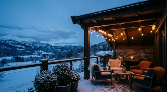 Patio coperto in inverno con luci calde e atmosfera accogliente, vista serale con neve sui mobili esterni