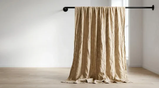 Tenda in lino stropicciato color sabbia con pieghe naturali illuminate da luce soffusa